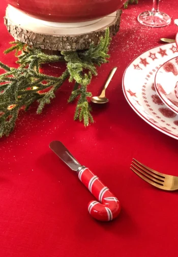 Cuchillo de untar con mango de bastón de caramelo sobre un mantel rojo de Navidad